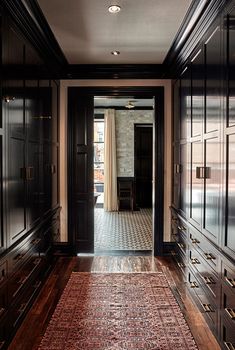 a hallway with dark wood cabinets and an area rug on the floor in front of it