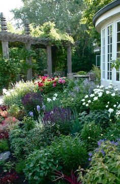 a garden filled with lots of flowers next to a house