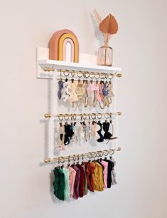 a white shelf with several pairs of earrings hanging on it