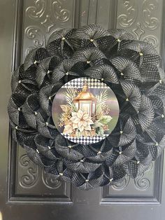 a black mesh wreath with a white and gold lantern on it's front door