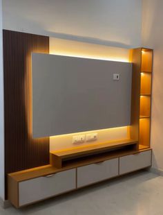 an entertainment center with a large television mounted on it's side, lit up by recessed lighting