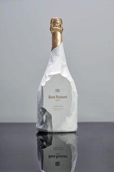 a bottle of dom rummant is wrapped in foil and sitting on a reflective surface