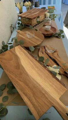 several wooden cutting boards sitting on top of a table covered in leaves and greenery