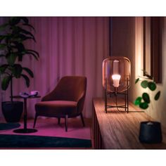 a table lamp sitting on top of a wooden shelf next to a chair and potted plant