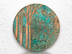 a round metal plate with trees painted on it