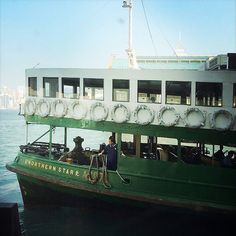 a large green and white boat with people on it's deck in the water