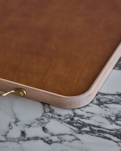 a close up of a wooden tray on a marble counter top with gold handles and brass hardware