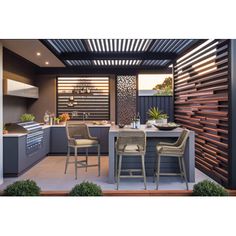 an outdoor kitchen and dining area with wooden slatted screens on the side wall