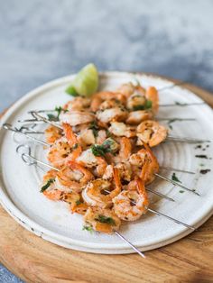 shrimp skewers on a plate with lime wedges