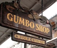 a sign hanging from the side of a building that says gumbo shop and creoe cuisine