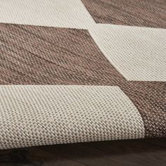 a brown and white checkered rug on top of a wooden floor