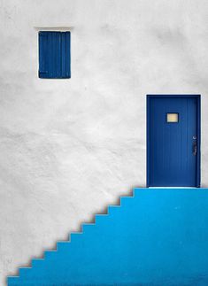 a blue door is on the side of a white building with steps leading up to it