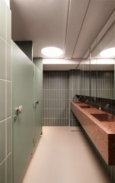 a public restroom with two sinks and green tiled walls on either side of the stalls