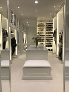 a walk in closet filled with lots of white furniture and shelves full of shoes on top of them