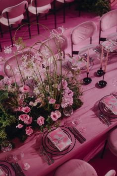 the table is set with pink flowers and place settings