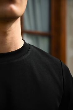 a man wearing a black t - shirt is holding his cell phone in his hand