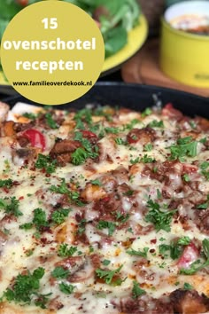 a pizza sitting on top of a pan covered in cheese and toppings next to a salad