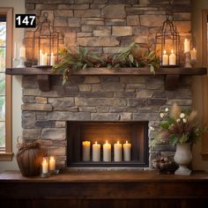 a fireplace with lit candles and greenery on the mantle in front of it is shown