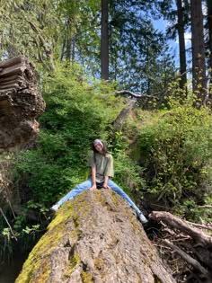 a man sitting on top of a large rock next to a forest filled with trees