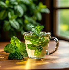 a glass cup filled with mint tea on top of a wooden table