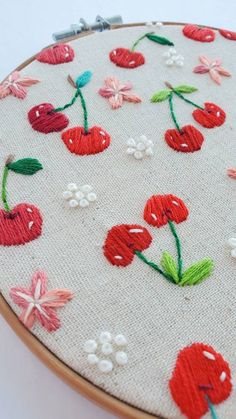 a close up of a embroidery on a piece of cloth with flowers and cherries