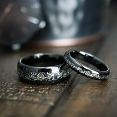 two wedding rings sitting on top of a wooden table