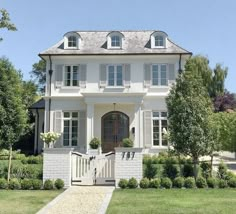 a large white house sitting on top of a lush green field