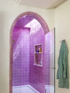 a bathroom with purple tiles on the shower wall and floor, along with a towel rack