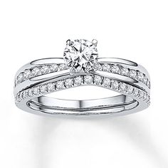 a white gold engagement ring set with two rows of diamonds on the band and a round diamond