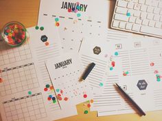 several calendars and pens on top of a desk with a keyboard, mouse and paper