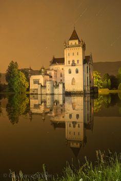 a castle sitting on top of a lake surrounded by trees