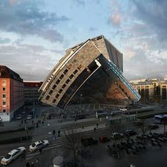 an upside down building in the middle of a parking lot with cars parked around it