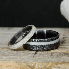 two wedding rings sitting on top of a wooden table