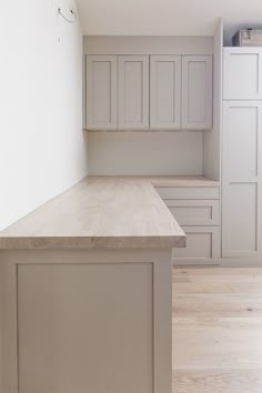 an empty kitchen with white cabinets and wood flooring