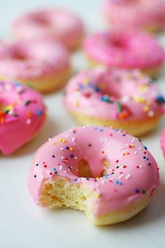 pink frosted doughnuts with sprinkles on white table top next to each other