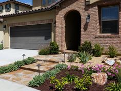 a house with landscaping in front of it and two garage doors on the other side