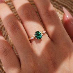 a woman's hand with a green and white diamond ring on her left hand