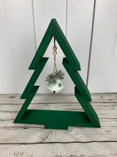 a wooden christmas tree with a potted plant hanging from it's side on a white wood floor