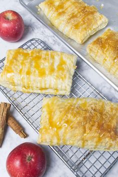 baked pastries on cooling racks next to apples and cinnamon sticks