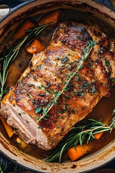 pork chops in a pot with carrots and rosemary garnish on the side