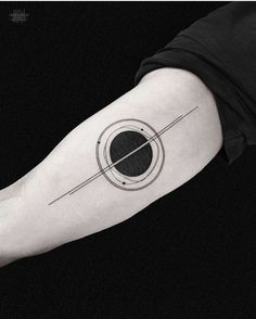 a black and white photo of a person's arm with a saturn tattoo on it