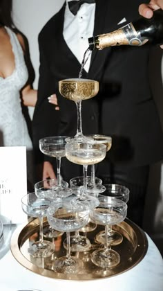 champagne being poured into wine glasses in front of a bride and groom