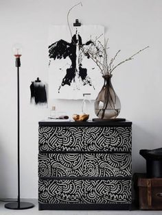 a black and white dresser in a room with art on the wall, vases and other items