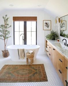 a bathroom with a rug, sink and bathtub next to a window in it