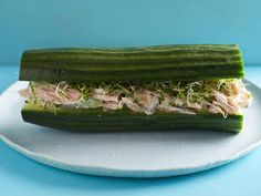 a cucumber with tuna and sprouts on it sitting on a plate