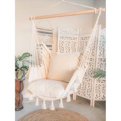 a white hanging chair in a room next to a potted plant and wicker furniture