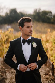 a man in a tuxedo standing next to a vineyard