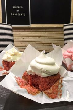 three cupcakes with white frosting and pink icing on paper wrappers