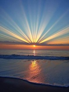 the sun is setting over the ocean with bright rays coming out from it's horizon