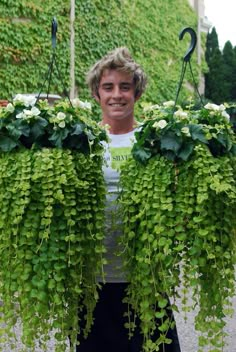 a man is holding two hanging plants in front of him